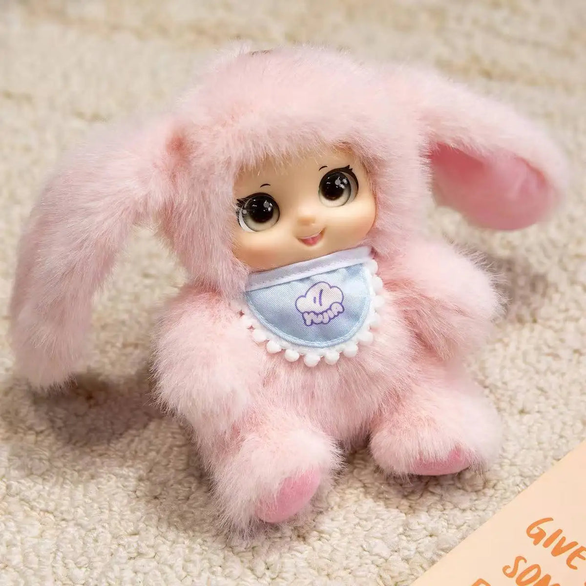 A soft pink plush pendant shaped like an animal face, featuring rabbit, bear, and sheep designs.