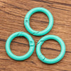 Four bright turquoise metal O-ring spring clasps arranged in a cluster on a wooden surface.