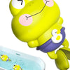 A yellow frog toy with a smiling face is floating in a clear bath container.