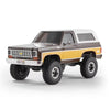A 1:24 scale Chevrolet K5 Blazer RC crawler in brown and white paint with large off-road tires.