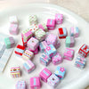 A variety of pink, green, and white acrylic flower print beads and bow charms are displayed on a white plate.