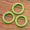 A set of ten bright lime green metal O-ring spring clasps arranged on a wooden surface.
