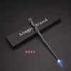 A dark wooden box holds a twisted, silver LED light-up magic wand with a glowing tip.