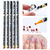 A hand holds a clear plastic pen with a black grip used to pick and apply rhinestones onto nails.
