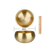 A brass Tibetan singing bowl with a hammered finish and a wooden mallet, shown next to a measurement guide.