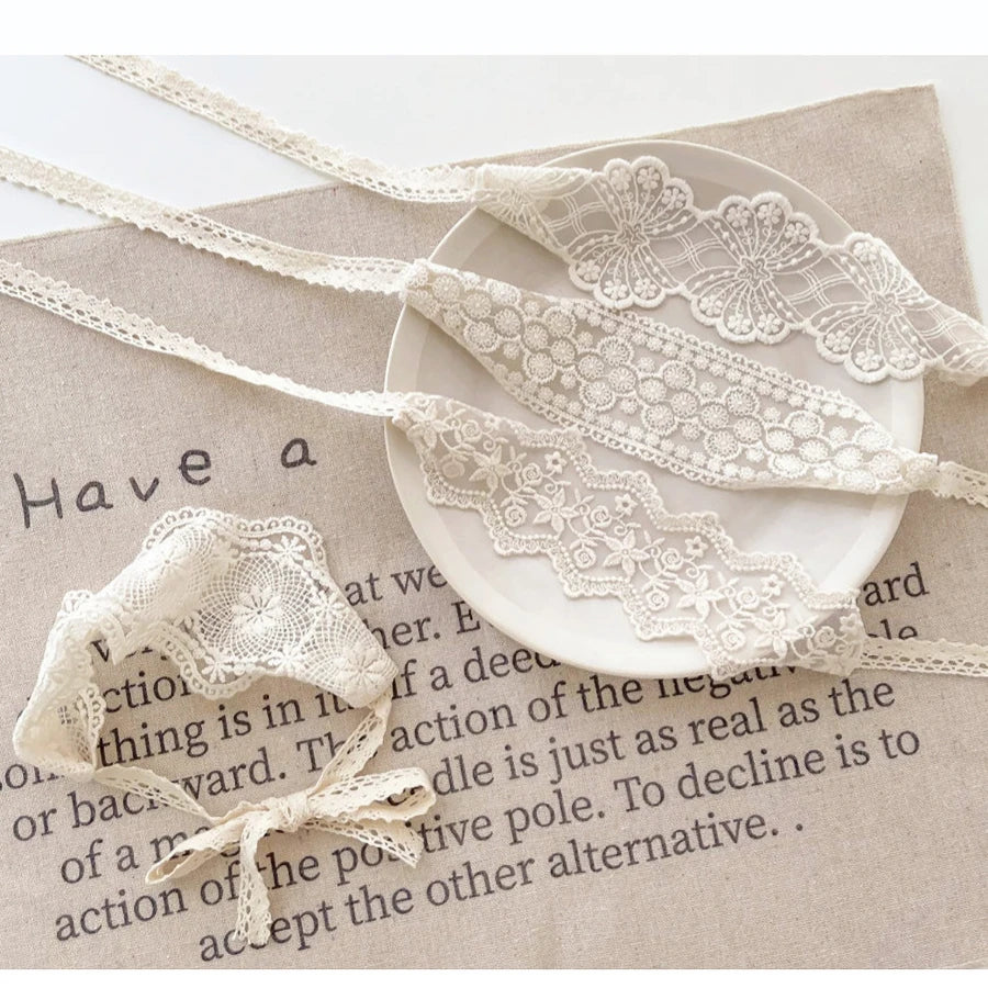 White floral lace baby headband for newborns displayed on a beige background.