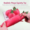 A hand squeezes a realistic pink pitaya squishy toy, showing its soft texture and vibrant color.