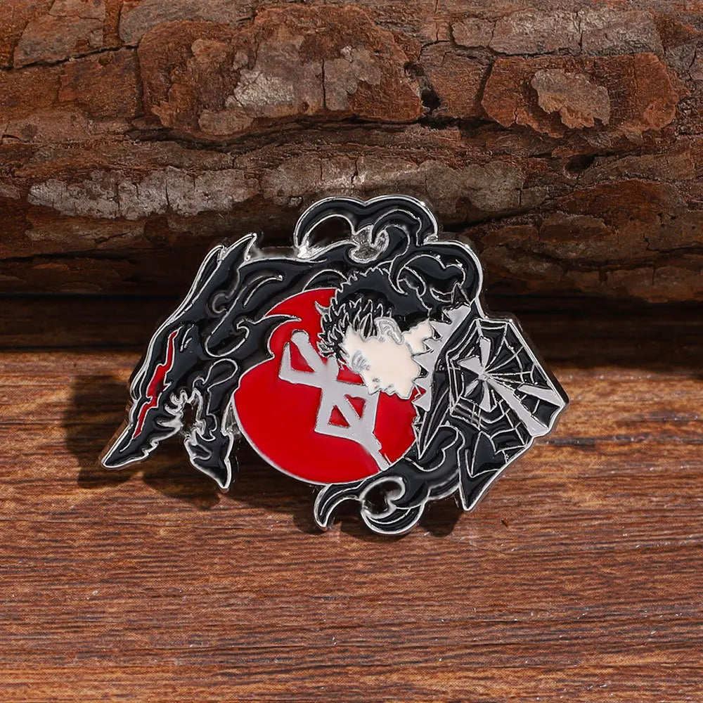 A silver enamel lapel pin featuring a stylized demonic face and a red circle with Japanese characters on a black background.