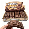 A box of chocolate bar squishy toys is shown with several brown squishy blocks and a single squishy toy being held by a hand.