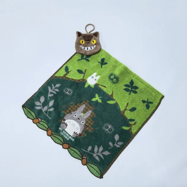 A green embroidered fabric featuring a small brown cat plush toy on a white background.