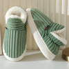 A pair of olive green faux fur slippers with white soles and light green ribbed fabric are shown on a white surface.