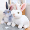 A pair of cute, soft plush rabbit toys in gray and white sitting on a surface.