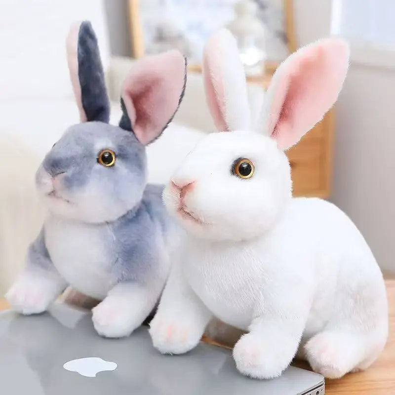 A pair of cute, soft plush rabbit toys in gray and white sitting on a surface.