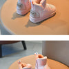 A pair of pink winter snow boots with faux fur lining and a non-slip sole resting on a light brown surface.