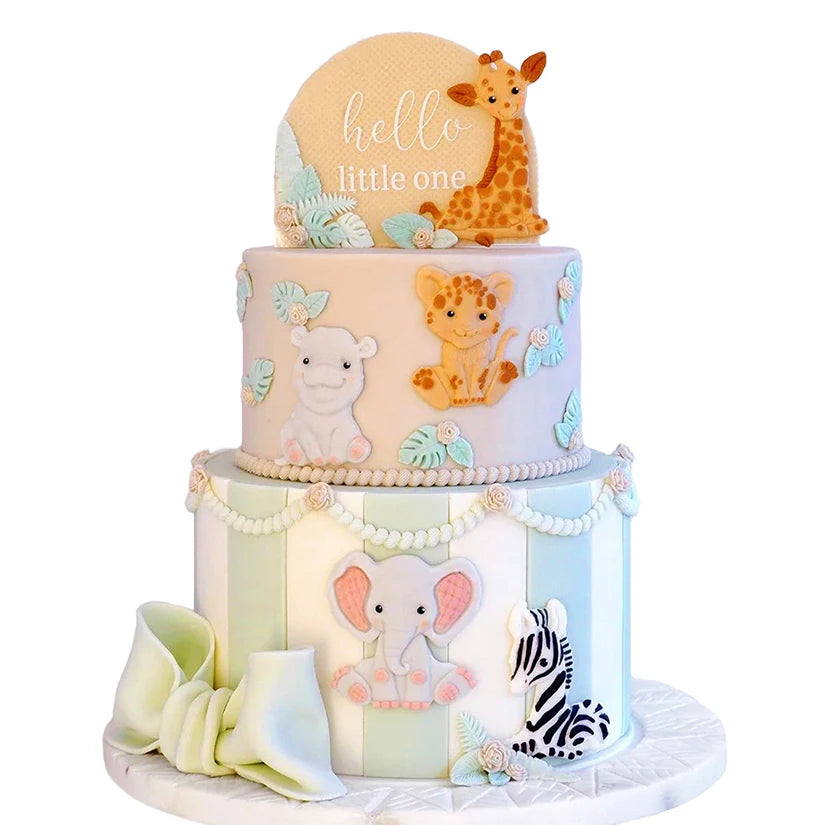 A tiered cake decorated with elephants and a giraffe, featuring pastel pink and green tones.
