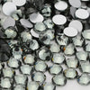 A close-up view of various clear and dark glass crystal flatback rhinestones for nail art and crafts.