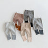 A collection of striped baby leggings in brown, gray, and black tones laid out on a white surface.