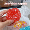 A hand holds a bright red squishy bead stress ball next to a clear white one on a laptop keyboard.