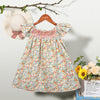A floral smocked summer dress for girls with flying sleeves displayed on a hanger.