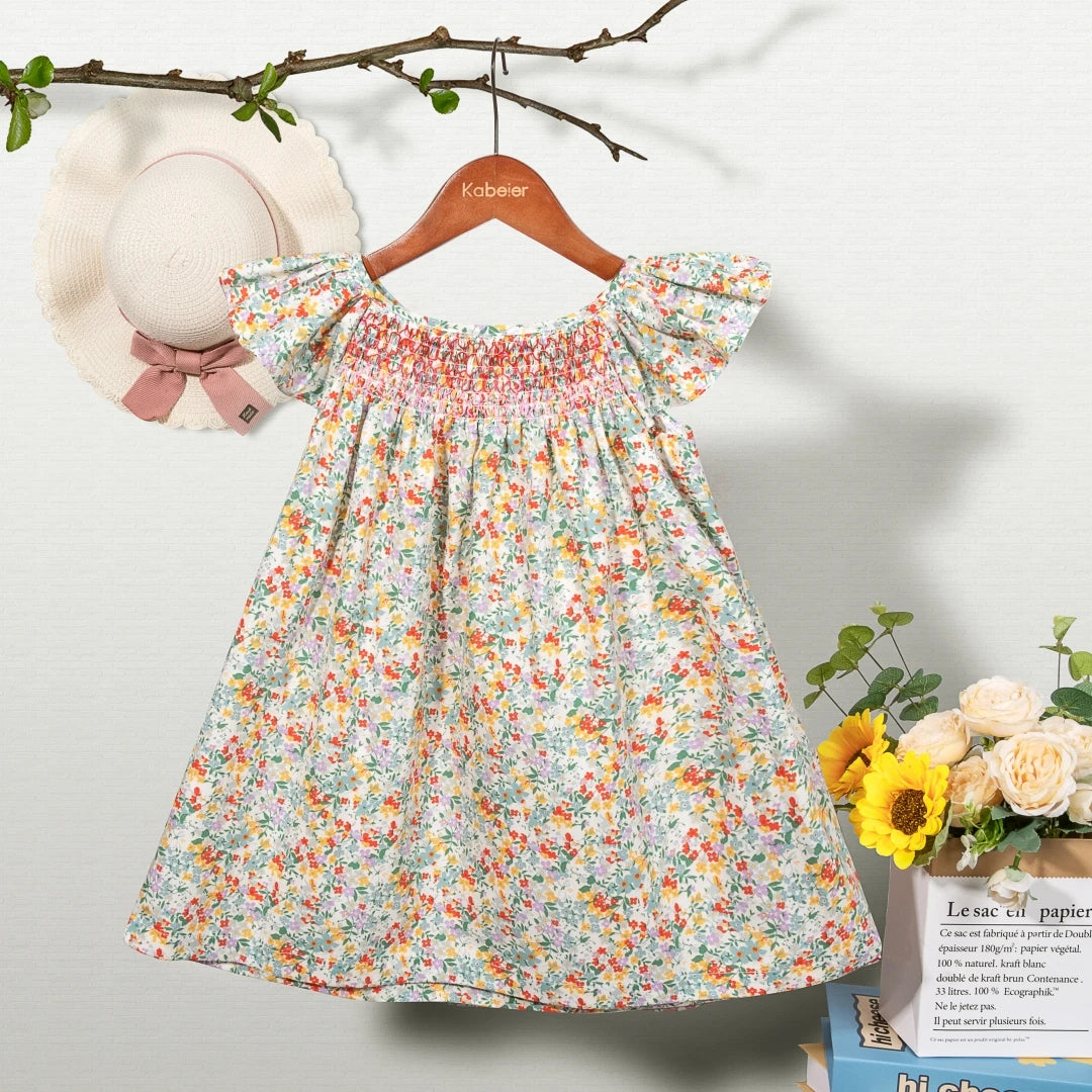 A floral smocked summer dress for girls with flying sleeves displayed on a hanger.
