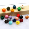 A collection of colorful natural wooden beads arranged on a light wooden board.