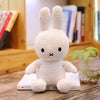 A white Miffy plush toy with long ears sitting on a wooden surface.