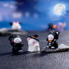 A collection of charming cartoon pumpkin bear figurines in black and white are displayed on a dark surface against a blue nig