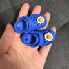 A pair of blue fashion slippers for a doll, featuring yellow daisy decorations.