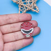A hand holds a red and white enamel pin featuring a dinosaur ranger battle suit and helmet design.