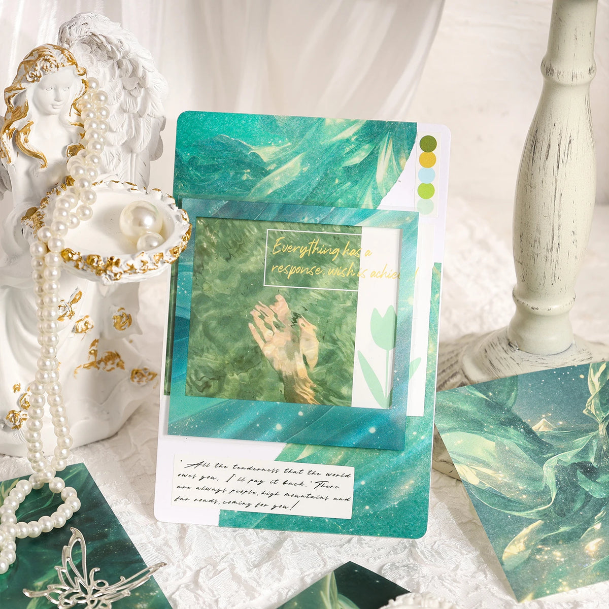A collection of vintage water wave gradient scrapbook paper sheets and a white ceramic figure are displayed on a white surfac