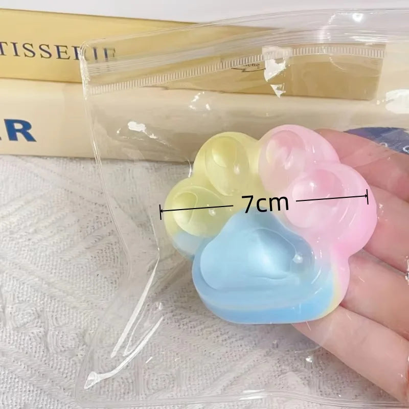 A hand holds a set of colorful silicone cat claw squeeze toys for stress relief and fidgeting.