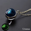 A pendant necklace featuring a blue and swirling sphere representing Uranus, with a green glow-in-the-dark charm.
