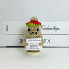 A handwoven crochet ornament shaped like a potato with a red hat and a sign encouraging positivity.