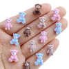 A hand displays various mini resin teddy bear charms in pink, blue, and brown colors.