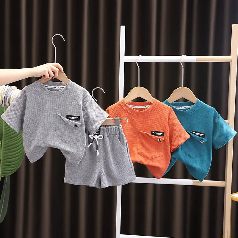 A gray t-shirt and matching gray shorts set are displayed on a wooden hanger against a white rack.