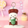 A cute white Miffy character in a red polka-dot outfit holding a green cupcake, presented as a blind box keychain.