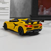 A yellow diecast supercar model with a black spoiler and open doors is displayed on a white surface.