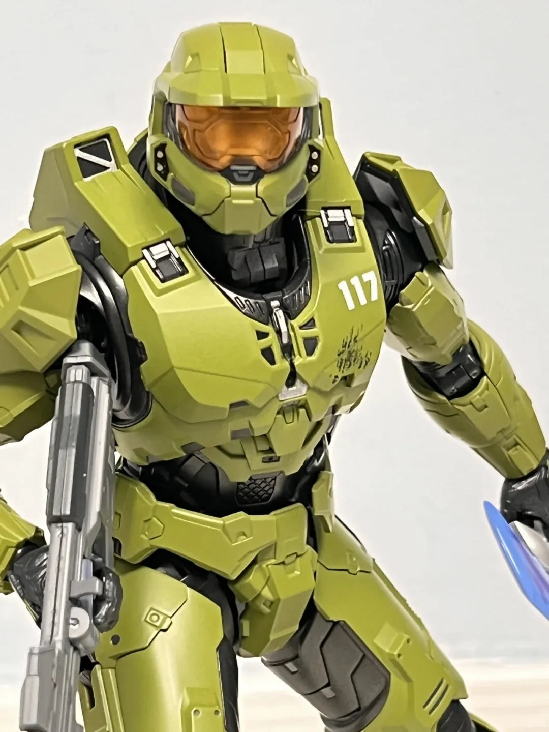 A 1/12 scale Master Chief action figure in olive green armor with an orange visor.