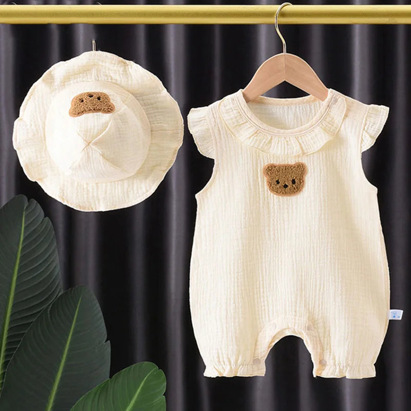 A cream cotton muslin baby romper and hat set featuring a bear applique.