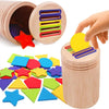 A wooden coin and color sorting toy with various colored plastic shapes scattered next to the container.