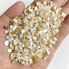 A handful of natural tumbled stone chips in various shades of beige and white stones for jewelry making