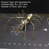 A detailed steampunk metal spider assembly kit with gold-colored legs and body resting on a dark grid background.