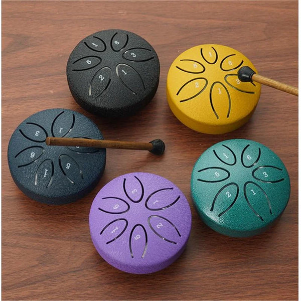 Five handmade steel tongue drum percussion instruments in various colors including black yellow purple and green