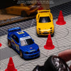 A yellow RC drift car is shown on a grid with red traffic cones, set against a dark background.