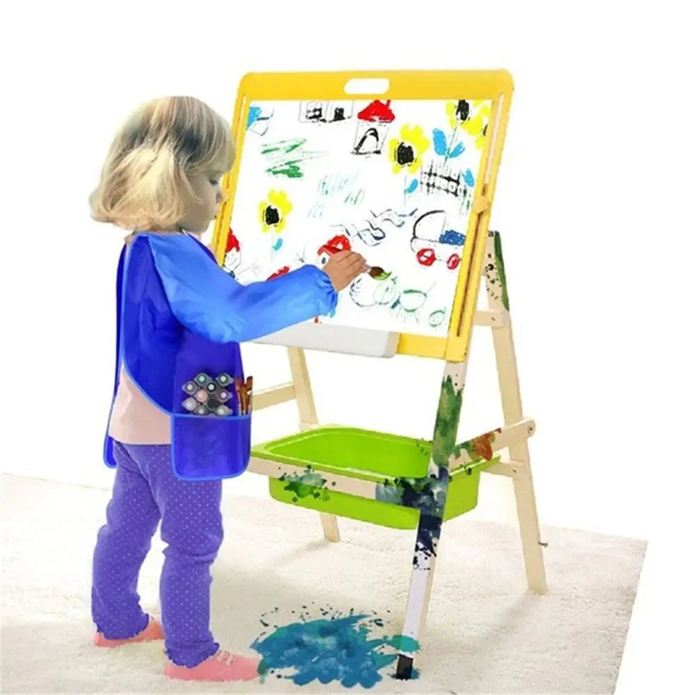 A young child is painting on a large yellow easel with an art apron, creating colorful artwork.