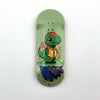 A wooden fingerboard deck featuring a green dinosaur graphic on a light green background.