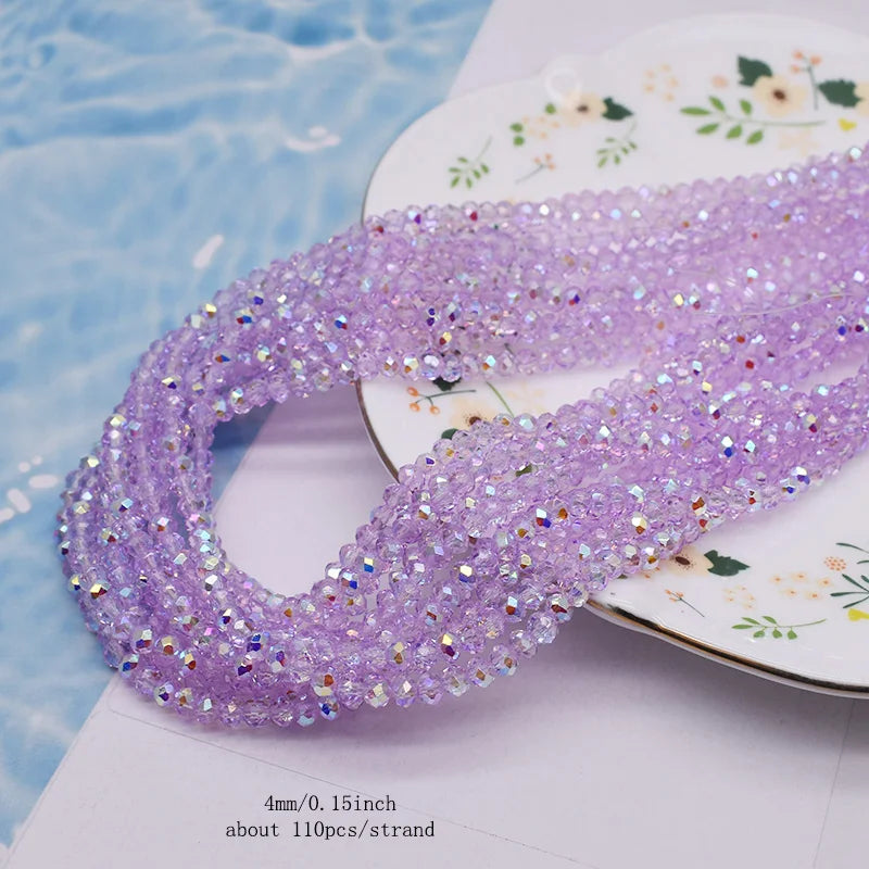 Purple faceted crystal rondelle beads for jewelry making displayed on a white surface.