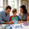 A family is shown assembling origami paper airplanes from a kit on a table.