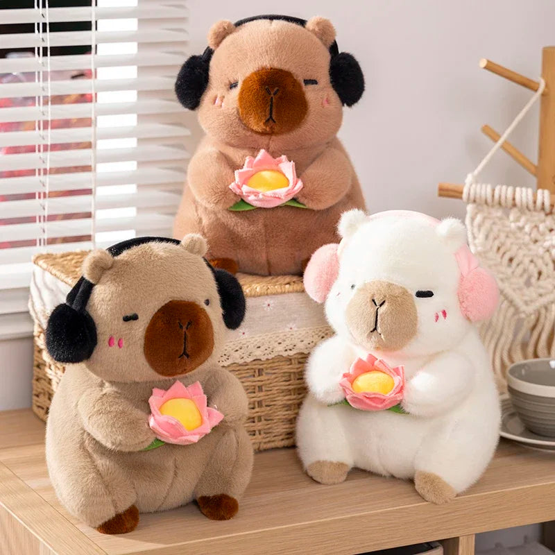 Two cute capybara plush toys, one brown and one white, are sitting together holding pink lotus flowers.