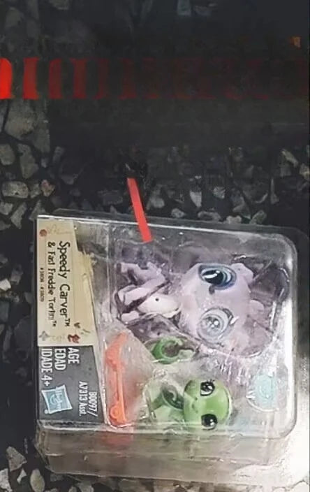 A clear plastic package containing three small animal figures, including a red stick, for sale.
